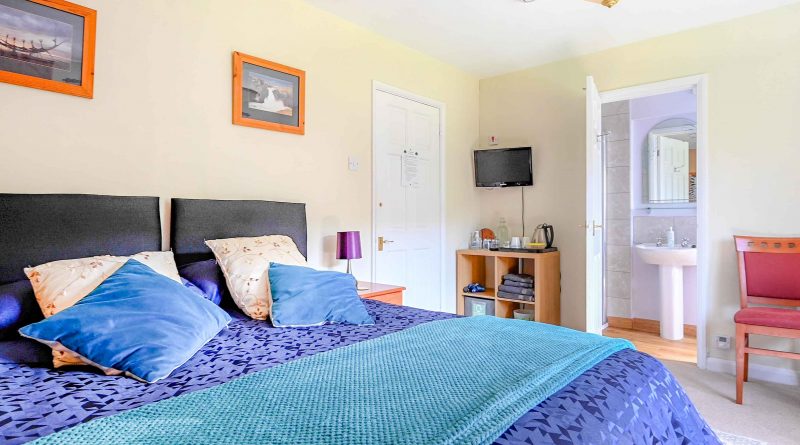 Double Room with blue duvet cover. View through to ensuite and tea/coffee making facilities