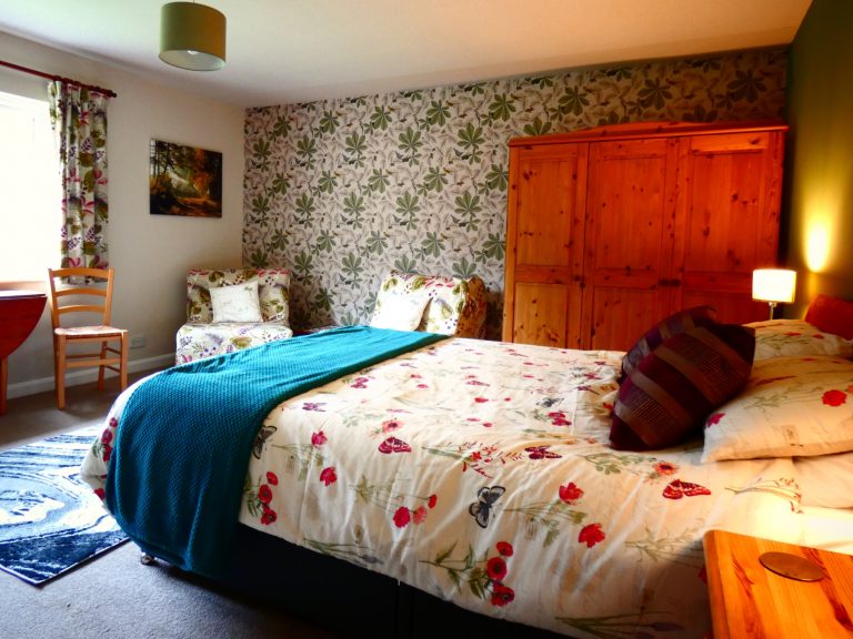 Family room with king size bed in foreground. Showing revised woodland themed wallpaper