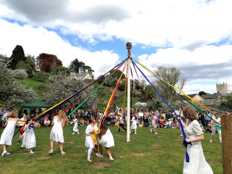 Lustleigh May Day celebrations. Children dressed in white dancing around a Maypole