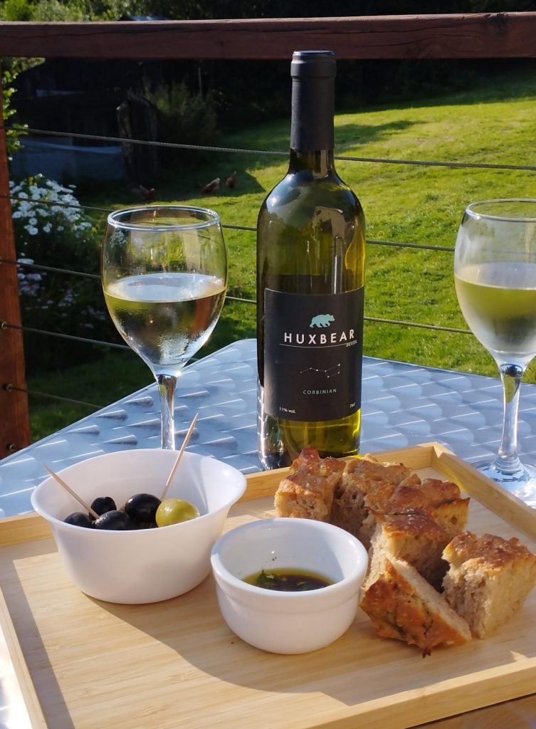 Foccacia with olives, balsamic vinegar and oil dip and two glasses of Huxbeare Corbinian white wine. On the deck overlooking the garden