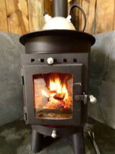 Outbacker 5kw logburner in Stables Eco-Bothies. Kettle warming on top of stove